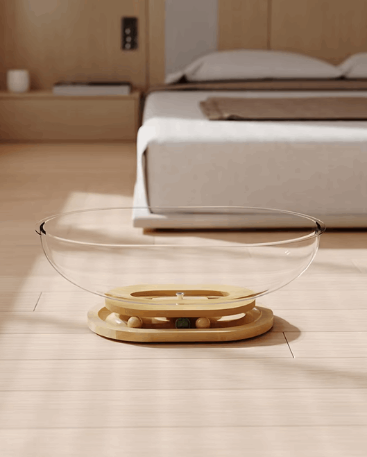 Clear glass bowl with wooden base on a wooden floor in a bedroom setting